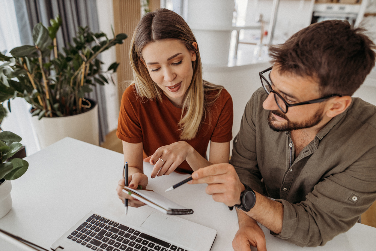 a man with glasses and a women looking at a notepad looking over their finances